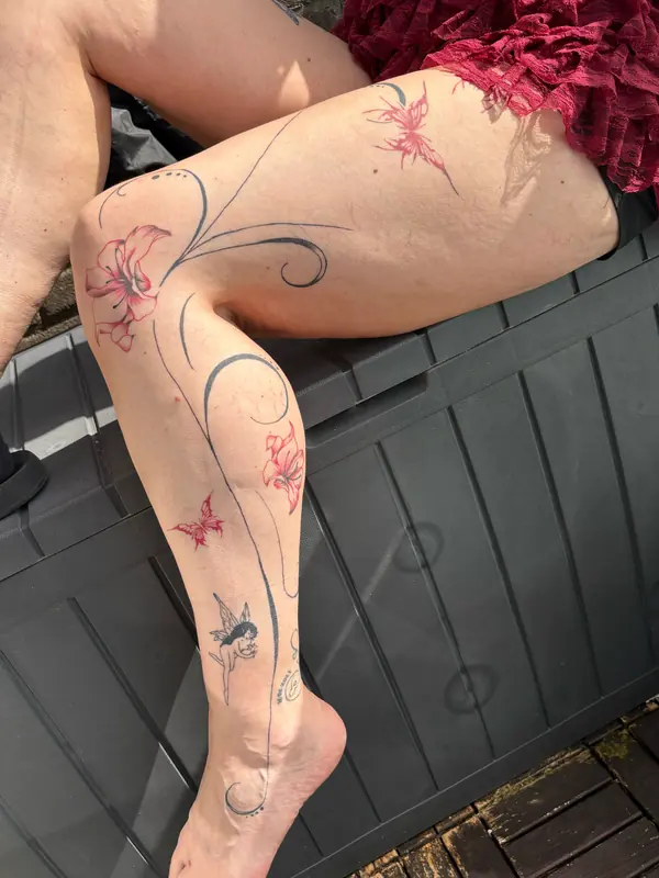 Flowing blackwork over het hele been met rode vlinders en een fee